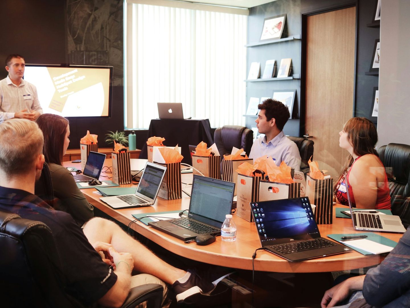 A large international team gathered around a boardroom table with laptops