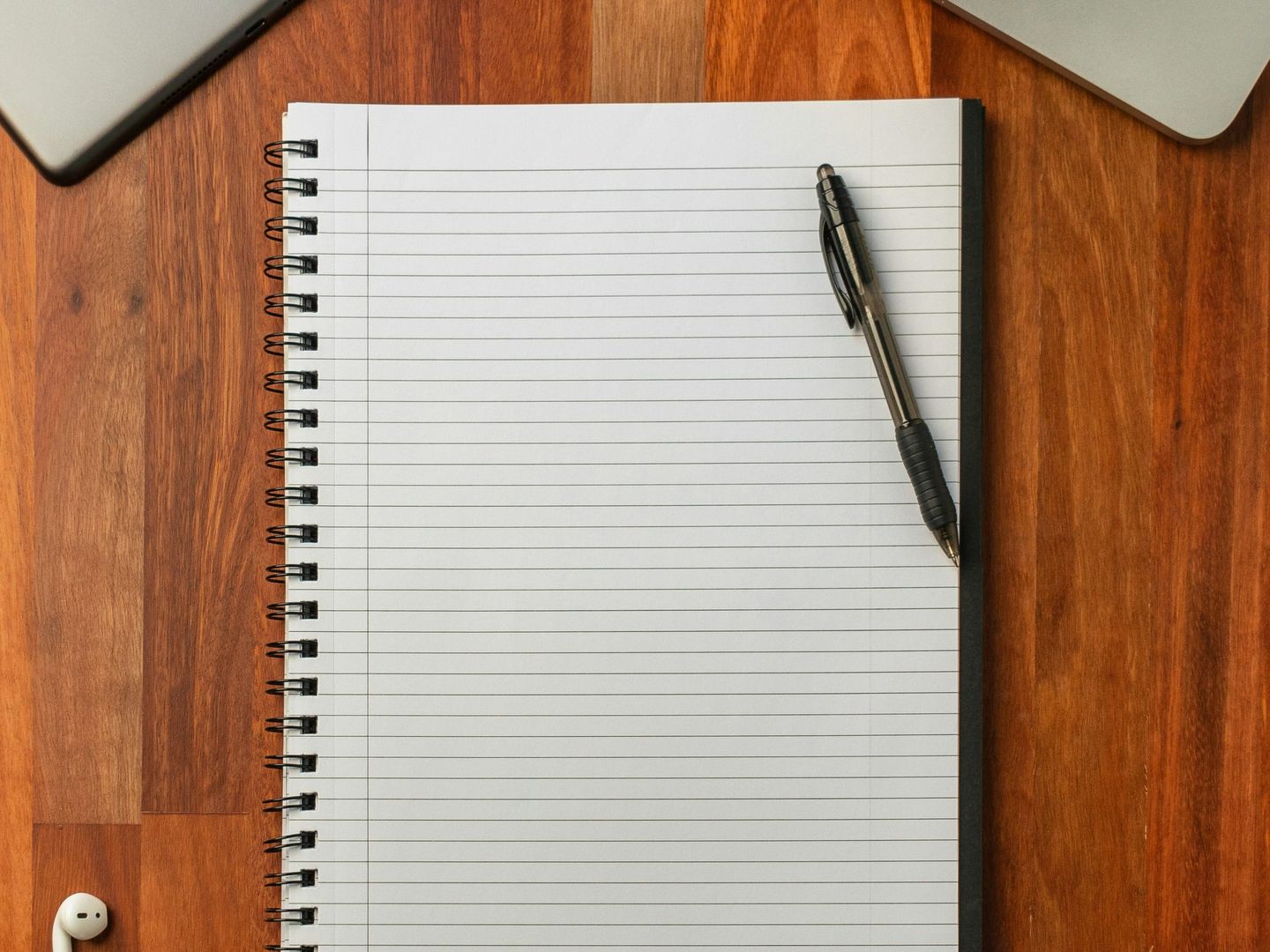 A notebook, pen and laptop laid out on a desk for planning
