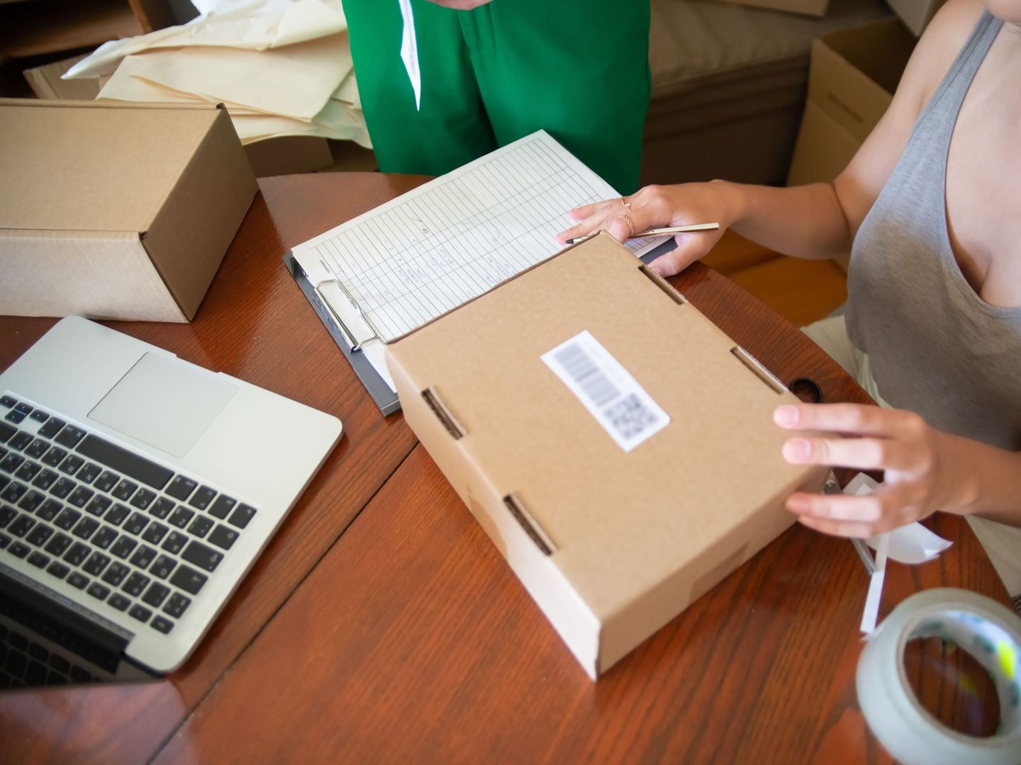 Een online verkoper die bestellingen inpakt naast een laptop